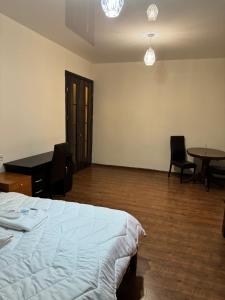 第比利斯Tbilisi pekini avenue Saburtalo的一间卧室，里面有一张床、一张桌子和几把椅子。 更多1张照片