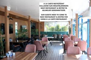 a restaurant with pink chairs and tables and windows at Mavi Restaurant & Apartments 2 in Didim
