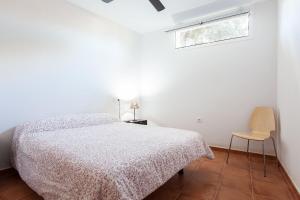 1 dormitorio blanco con 1 cama y 1 silla en La Casa Del Volcán De Cabo De Gata, en Las Hortichuelas Bajas