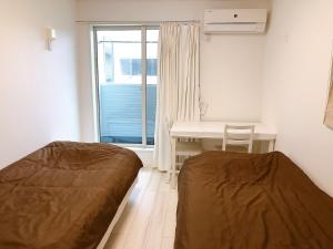 镰仓市Ano House 女性専用Women's Guesthouse的配有书桌和窗户的客房内的两张床