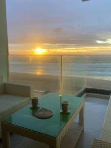a table with two cups on a balcony with the sunset at Panoramic view Condo Mehdia in Kenitra