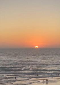 a sunset over the ocean with people on the beach at Panoramic view Condo Mehdia in Kenitra +5 photos