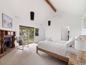 ein weißes Schlafzimmer mit einem Bett und einem Kamin in der Unterkunft Pelicans View a Riverside Retreat in Augusta