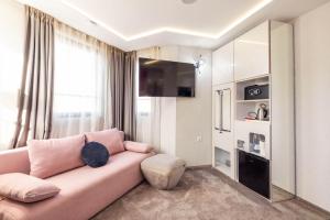 a living room with a pink couch and a window at Aurora Hills Hotel in Plovdiv