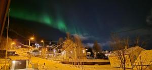 Una aurora en el cielo sobre un pueblo con casas. en Villa Aurora Casita, en Tromsø 22 fotos más