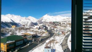 a view of a snowy mountain from a window at Marco Polo, Mountain View Apartment in Gudauri +1 photo