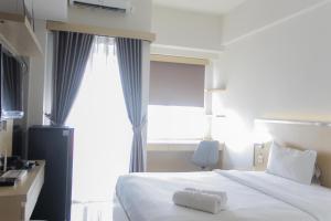a bedroom with a large white bed with a window at Comfort Minimalist Studio at Parkland Avenue Apartment By Travelio in Tangerang
