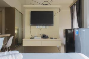 a room with a tv and a desk with a refrigerator at Comfort Minimalist Studio at Parkland Avenue Apartment By Travelio in Tangerang