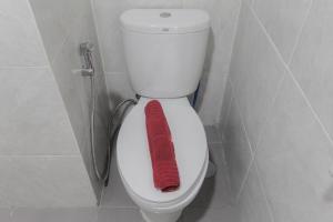 a red towel sitting on a toilet in a bathroom at Comfort Minimalist Studio at Parkland Avenue Apartment By Travelio in Tangerang +6 photos