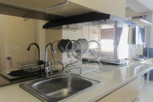 a kitchen sink with dishes in drying rack above it at Comfort Minimalist Studio at Parkland Avenue Apartment By Travelio in Tangerang