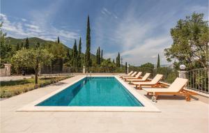 a pool with chaise lounge chairs and a swimming pool at Amazing Home In Bijeli Vir in Bijeli Vir