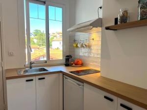 a kitchen with white cabinets and a sink and a window at Studio lumineux à 100m de la plage ! in Saint-Jean-de-Luz