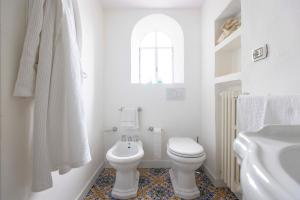 a white bathroom with a toilet and a sink at Villa Giggione in Erchie