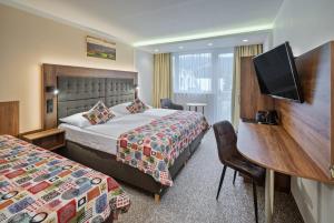 a hotel room with two beds and a flat screen tv at Wellness Hotel Astra in Špindlerův Mlýn
