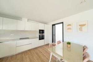 Una cocina con gabinetes blancos y una mesa y sillas. en Villa Borghese, en San José