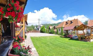 a yard with red flowers and a house at Casa Discret Moieciu in Moieciu de Jos