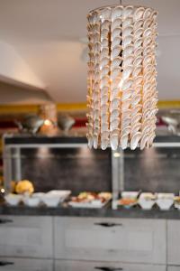 a chandelier in a kitchen with plates of food at Apartmenthotel am Leuchtturm in Hörnum