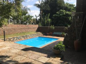 una piscina en un patio con una pared de ladrillo en Birrea Guest house, en Polokwane