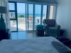 1 dormitorio con 1 cama, 1 silla y balcón en Hawaan View, en Durban 10 fotos más