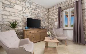 un soggiorno con 2 sedie e una TV su un muro di pietra di Villa Lucija Dream a Trgetari