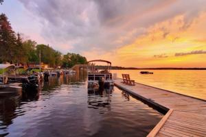 a dock with a boat in the water at sunset at Marina View 1 Bedroom Sunset Cabin in Kabetogama +9 photos