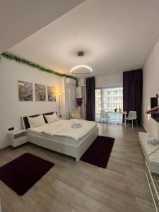 a bedroom with a white bed and a living room at Ametist in Mamaia