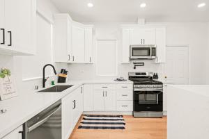 a white kitchen with white cabinets and a stove top oven at Cozy Retreat Near Downtown - Perfect for Families in Long Beach