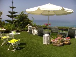a group of chairs and an umbrella on the grass at Palmina Mare in Paralia Vrachou