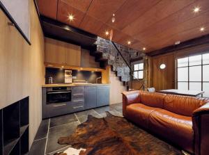 a living room with a leather couch and a kitchen at The Old Stable - Your Seaside Hideaway in Pittenweem