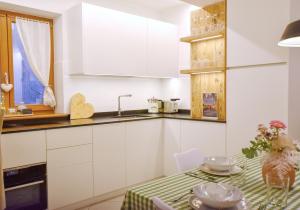a kitchen with white cabinets and a table at Dolomiten Lounge - moderno con parcheggio privato in Pergine Valsugana