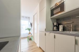 アヌシーにあるLac Pershing - Appartement confortable à deux pas du lacの白いキャビネットとシンクのあるキッチン