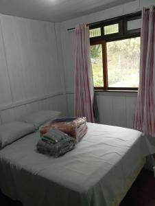 a bed in a room with two bags on it at MICRO CASA DE SITIO DO TIO Tonho in Blumenau