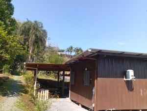 a brown and black shack with a porch at MICRO CASA DE SITIO DO TIO Tonho in Blumenau