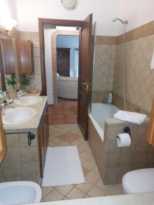 Un baño con dos lavabos, una bañera y una ducha. en Estanza nel verde, en Manziana