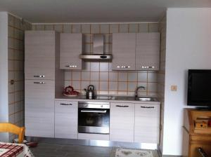 a kitchen with white cabinets and an oven at Almida in Castello di Fiemme