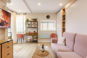 ein Wohnzimmer mit einem rosa Sofa und einem Tisch in der Unterkunft New! Cozy for couples with private patio in Sevilla