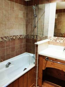 a bathroom with a bath tub and a sink at Studio 4 personnes pied des pistes avec piscine in Villarembert