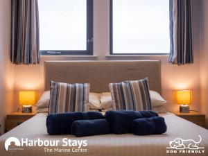 a bedroom with a bed with pillows and two windows at Harbour Stays - The Marine Centre, Saundersfoot Harbour, SA69 9HE in Saundersfoot +24 photos
