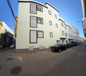 a large white building with cars parked in front of it at Edificio Mañez - Bajo in La Línea de la Concepción