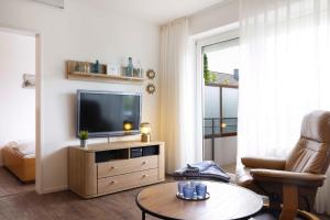 a living room with a television and a chair and a table at DKK1c Ferienwohnung Mole 1 in Niendorf