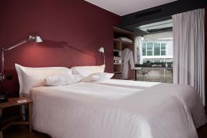 a bedroom with a large white bed with a red wall at Casa Camper Berlin in Berlin