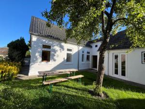 a picnic bench in front of a white house at Ferienhaus Stranden Westfehmarn in Fehmarn