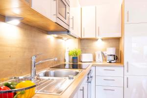 a kitchen with a stainless steel sink and white cabinets at DKK1c Ferienwohnung Mole 1 in Niendorf