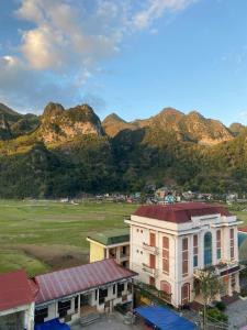 a building with a field and mountains in the background at Đồng Văn Hotel in Dồng Văn +34 photos