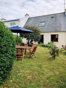 a table and chairs with an umbrella in a yard at Charmante maison proche plage et port in Camaret-sur-Mer