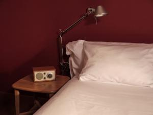 a bed with a table with a alarm clock and a lamp at Casa Camper Berlin in Berlin