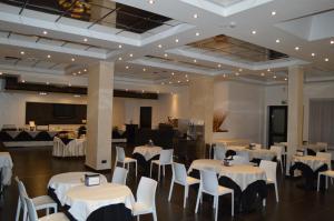 拉奎拉的住宿－Canadian Hotel，宴会厅配有白色的桌子和白色的椅子