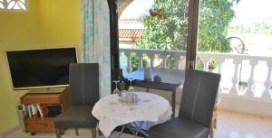 a living room with a table and chairs and a television at Confortable Estudio con Terraza, Piscina y Bbq in Icod de los Vinos