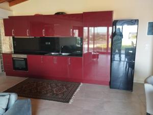 a kitchen with red cabinets and a person standing in it at Το πέτρινο 2 in Agia Marina Mikrolimanou
