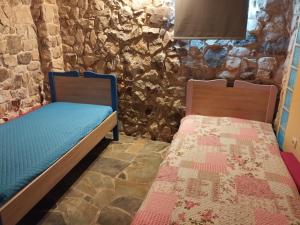 two beds in a room with a stone wall at Το πέτρινο 2 in Agia Marina Mikrolimanou